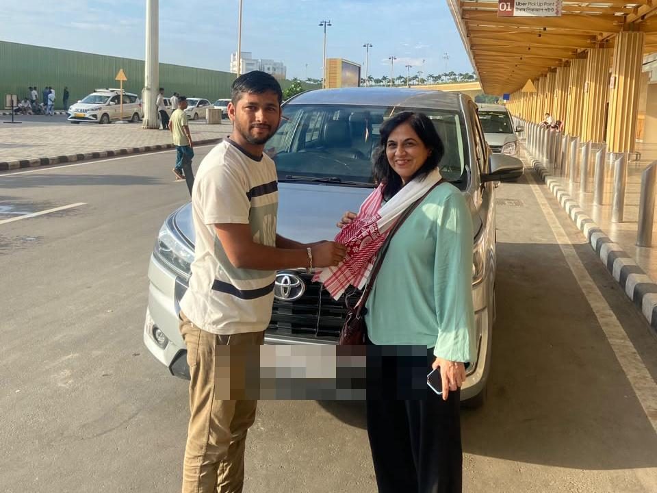 Happy Yatra Travels driver greeting a guest at the Guwahati airport pickup point with the Innova Crysta