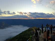 Travellers watching the sunset from a Meghalaya hilltop viewpoint above the clouds